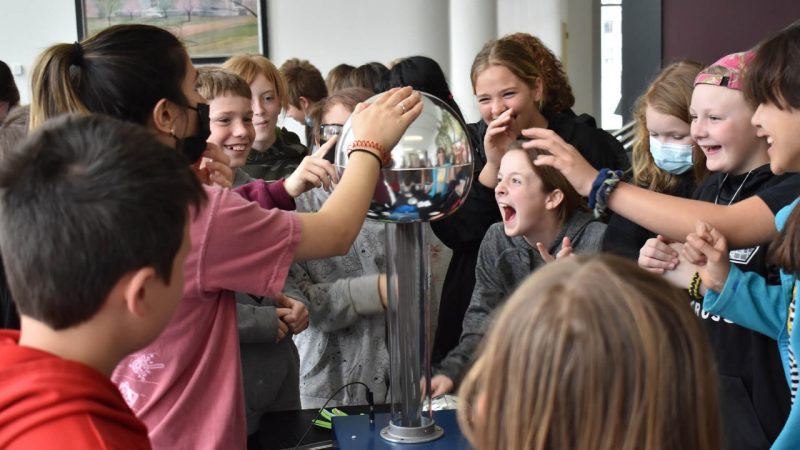 A Virginia Tech college student is demonstrating a Van de Graaff generator while fifth graders respond with excitement. Photo credit: Kalilah Kroll