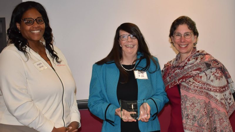 Emily Burns [center], holds her award alongside Angela Hayes [left] and Dean of Graduate Education Aimee Suprenant [right].