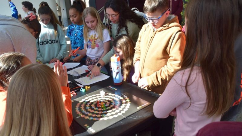 Students stand around an exhibit table