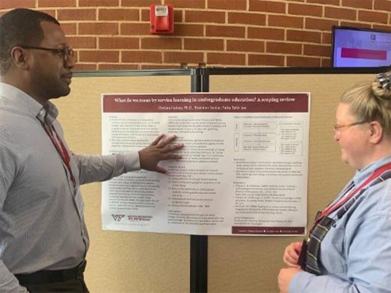 Brandon Senior (left) presents poster to conference attendee.